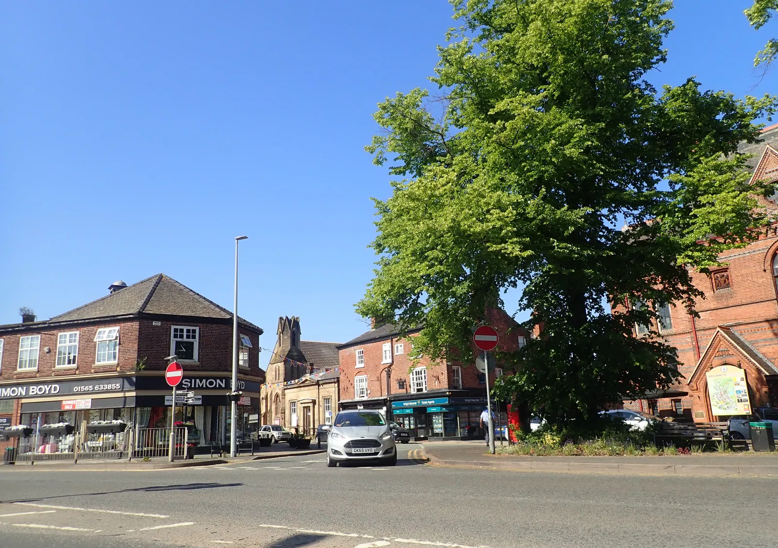 Brick buildings and a leafy tree in Knutsford town centre on a sunny day