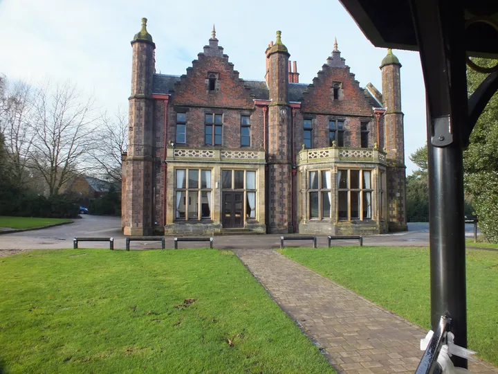 The brick and stone frontage of Walton Hall, viewed across its lawn